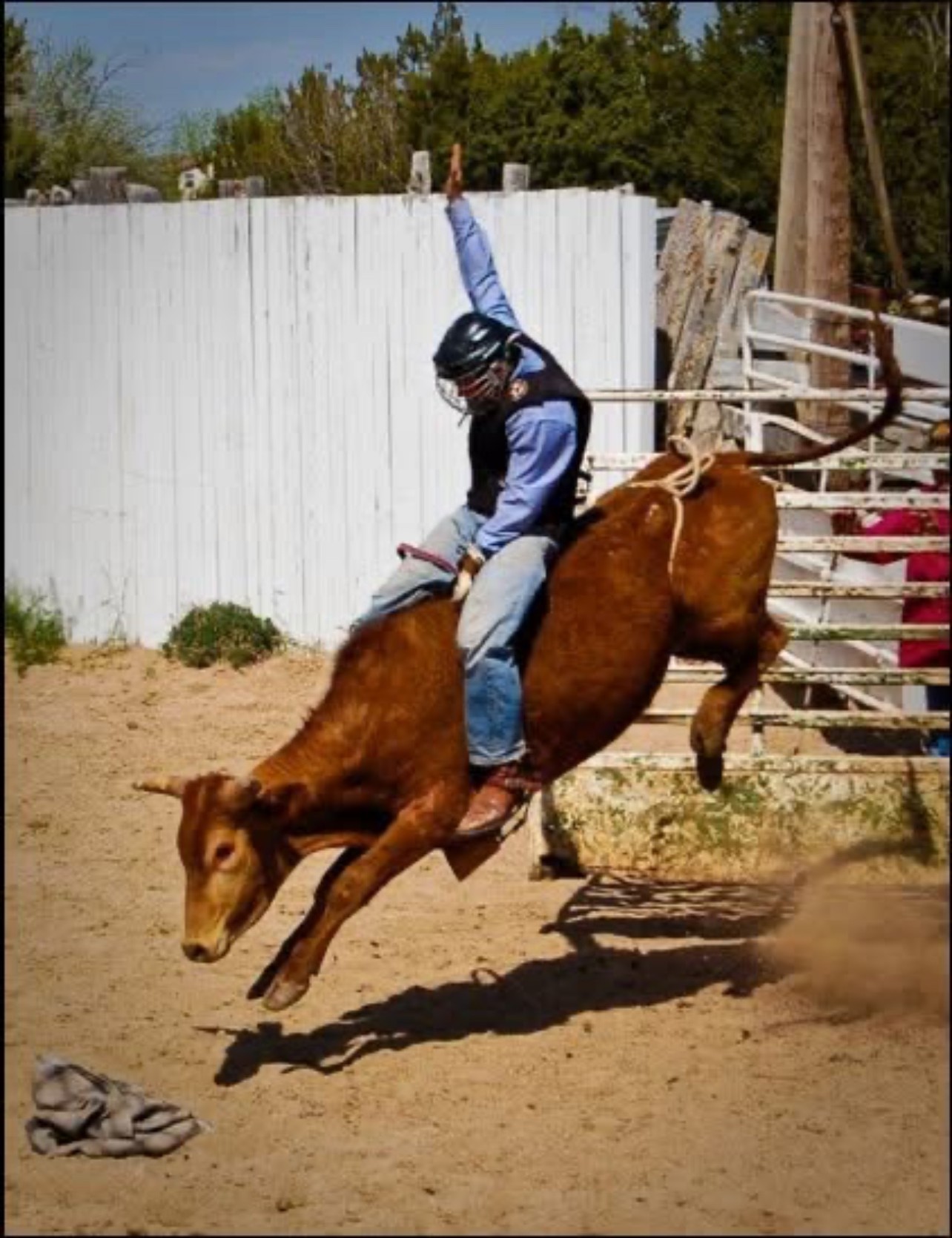 Cody riding a bucking bull at a rodeo, one hand in the air
